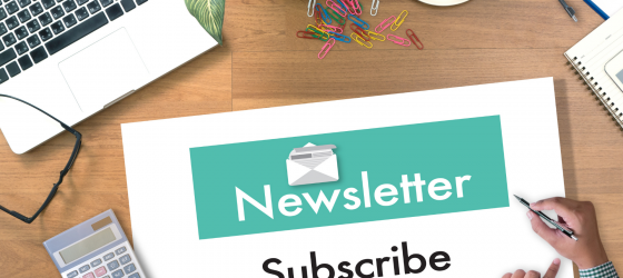 scritta newsletter su foglio bianco e verde posat su scrivania con pc